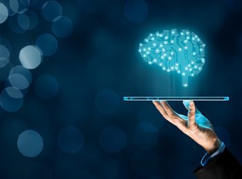 a hand holding a glass plate with a glowing brain